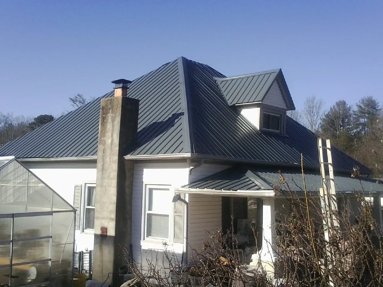 Dark blue standing seam metal roof on a white farmhouse with dormer — Slate & Tile Roof Repair by Roofing Brothers in Knob Lick