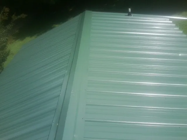 New green metal panels meeting at the ridge of a roof — Flat Roof Repair work by our crew in Knob Lick