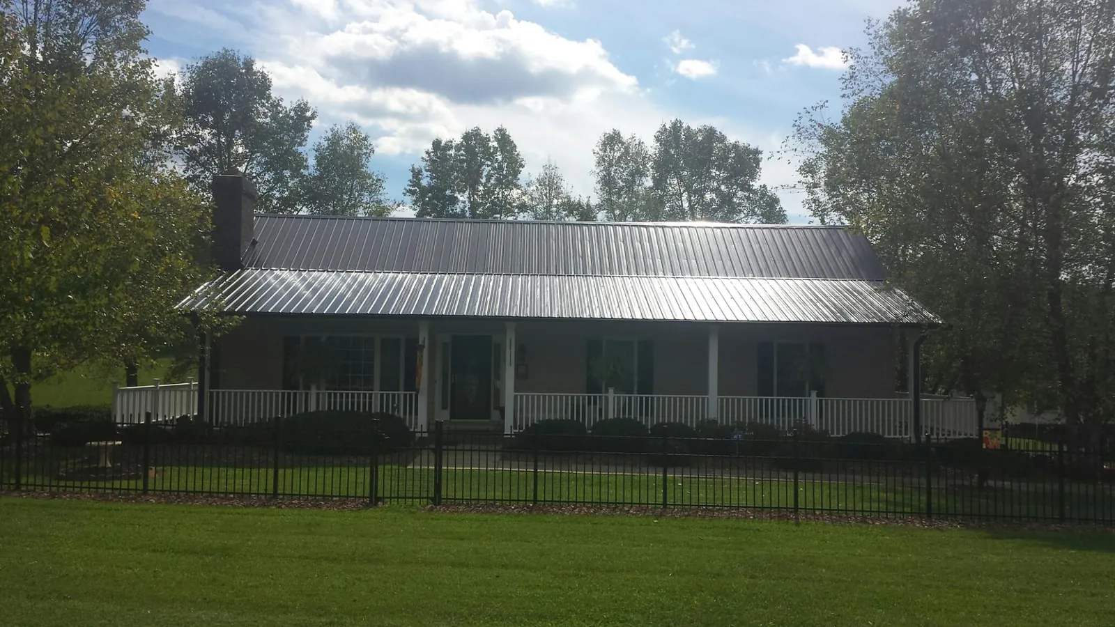 Gray metal roof on a brick ranch with a full width front porch — Gutter Guard Installation work by our crew in Knob Lick