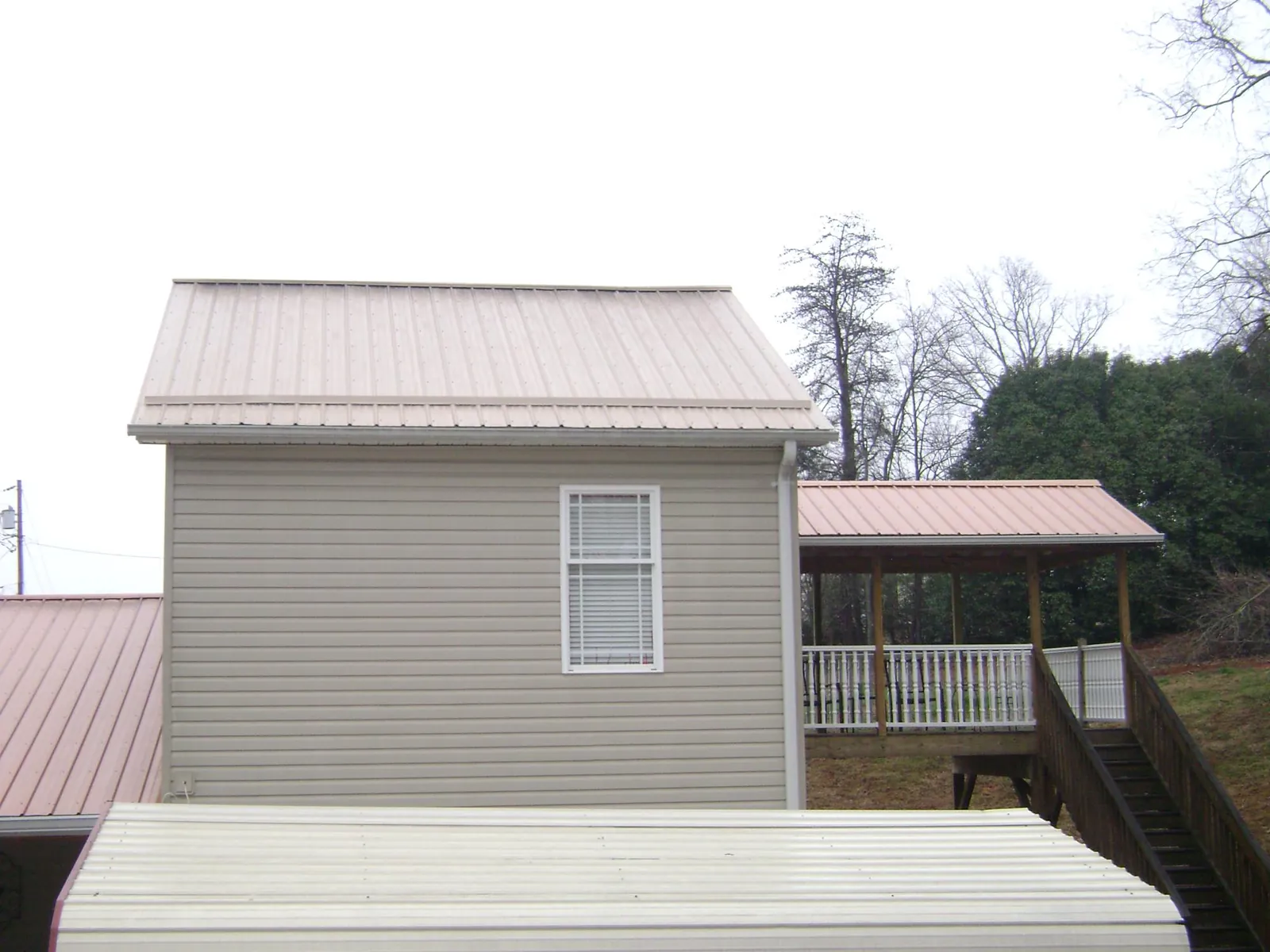 Tan metal roofs on a two story addition and attached porch, from a Roof Replacement job in Knob Lick