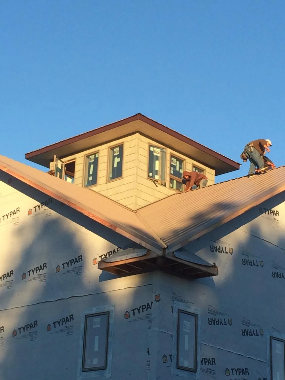Roofers working around a rooftop cupola on a new metal roof at sunset — Roof Waterproofing in Knob Lick by Roofing Brothers